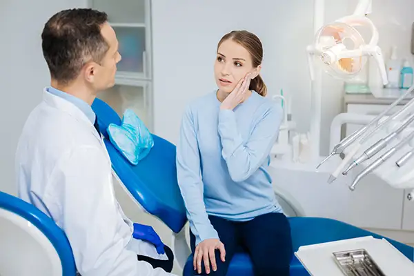 Concerced patient discussing her tooth pain with her surgeon while sitting in a dental chair at Downey Oral and Maxillofacial Surgery in Downey, CA