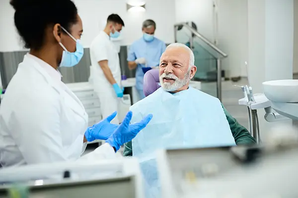 Older patient sitting in dental chair and listening to his dentist talk about dental implants at Downey Oral and Maxillofacial Surgery in Downey, CA